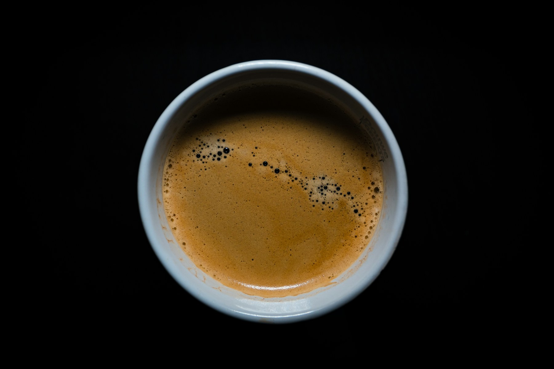 A close overhead view of rich coffee in a ceramic cup